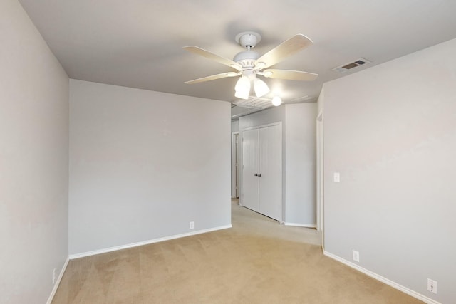 spare room with ceiling fan and light colored carpet