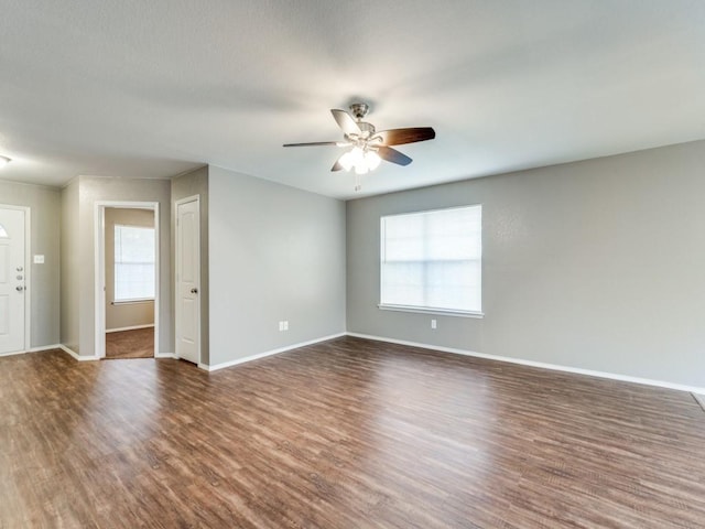 empty room featuring dark hardwood / wood-style flooring, plenty of natural light, and ceiling fan