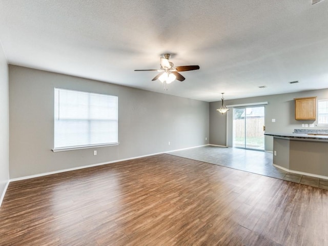 unfurnished living room with ceiling fan and dark wood-type flooring