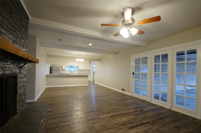 living room with beamed ceiling, a stone fireplace, dark wood-type flooring, and a textured ceiling