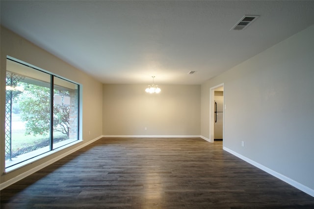 unfurnished room featuring dark hardwood / wood-style flooring and an inviting chandelier