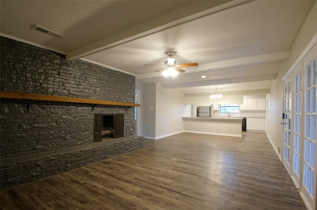 unfurnished living room featuring a textured ceiling, sink, beam ceiling, hardwood / wood-style floors, and a stone fireplace