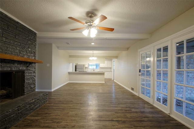 unfurnished living room featuring beamed ceiling, ceiling fan with notable chandelier, a stone fireplace, and a textured ceiling