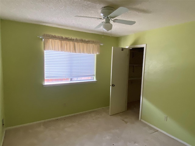 unfurnished bedroom featuring ceiling fan, a closet, a spacious closet, and a textured ceiling