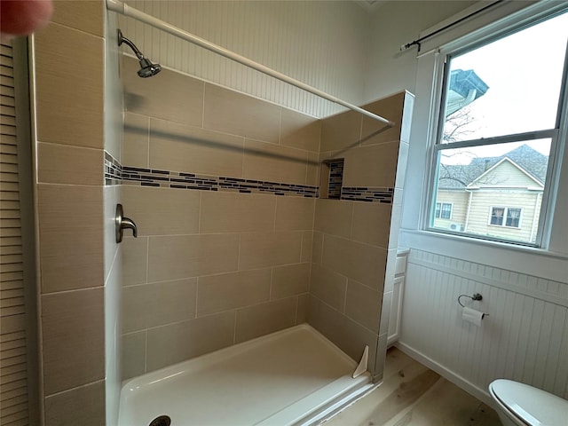 bathroom featuring hardwood / wood-style flooring, toilet, and tiled shower