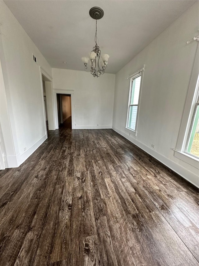 unfurnished dining area with dark wood-type flooring and an inviting chandelier