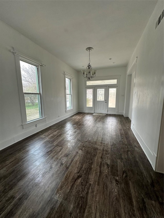 spare room with an inviting chandelier and dark hardwood / wood-style flooring