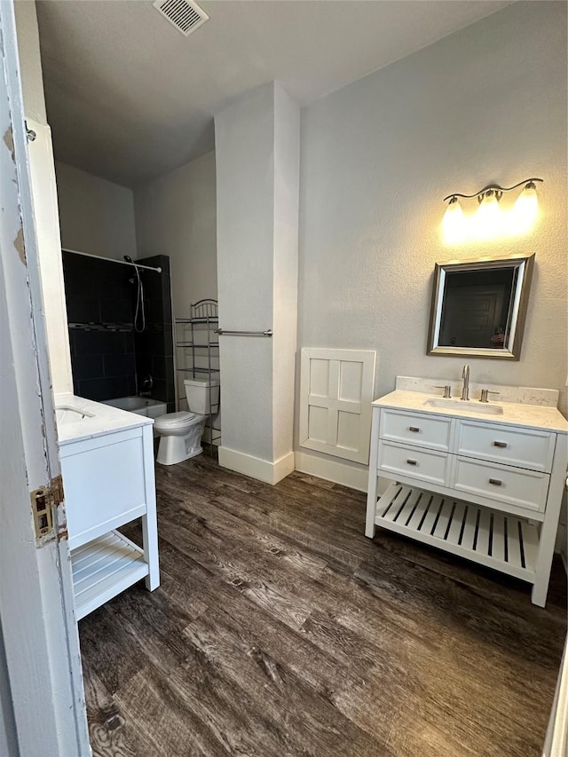 bathroom with hardwood / wood-style flooring, a shower, vanity, and toilet