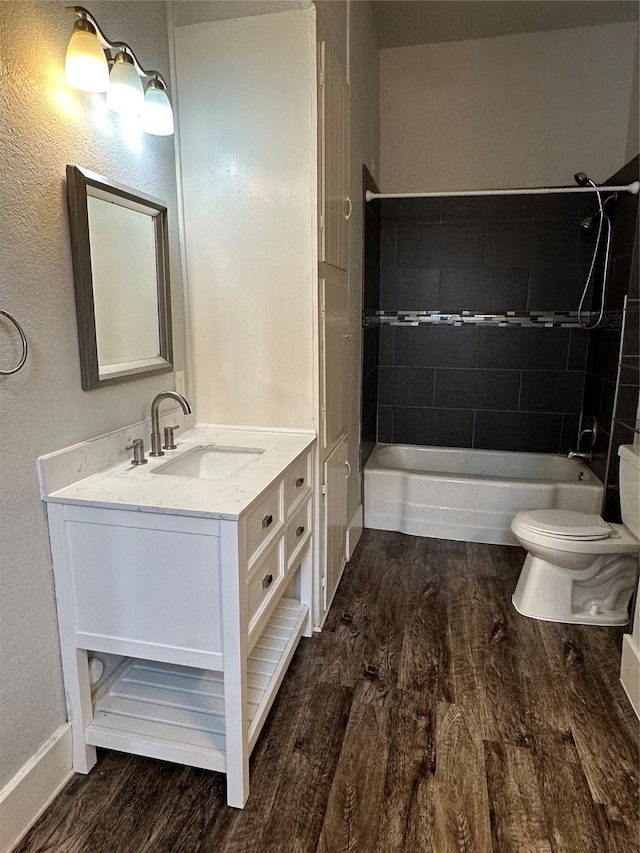 full bathroom with vanity, hardwood / wood-style flooring, toilet, and tiled shower / bath combo