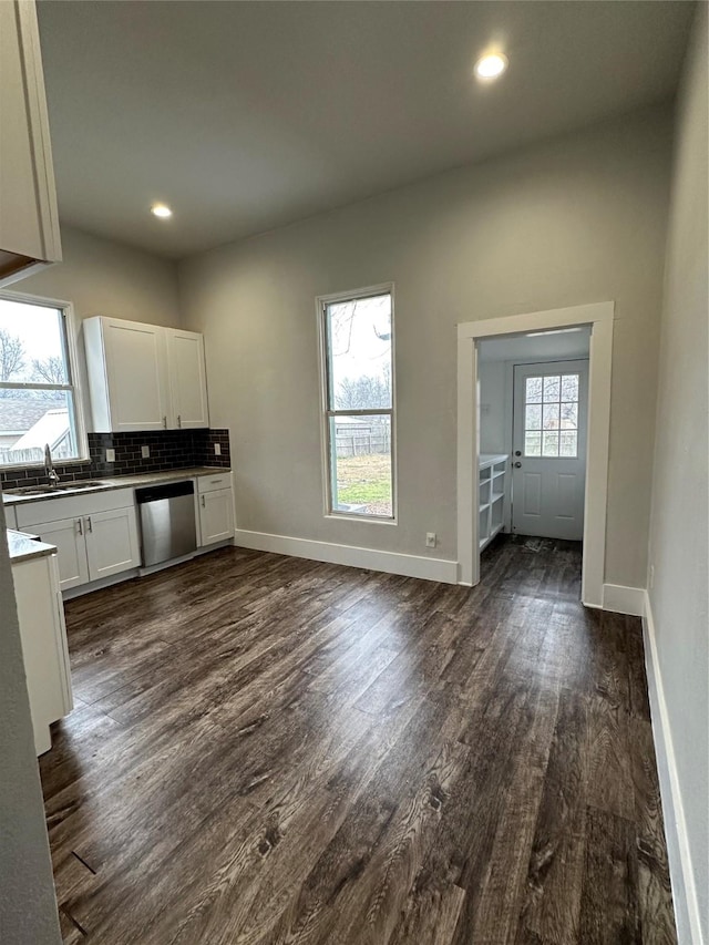 kitchen with dark wood-type flooring, sink, dishwasher, white cabinets, and backsplash