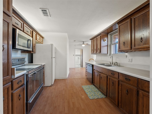 kitchen with appliances with stainless steel finishes, light hardwood / wood-style floors, ceiling fan, and sink