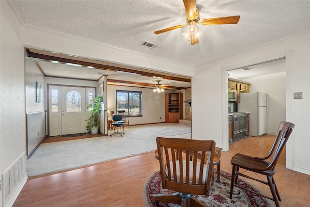 interior space featuring crown molding, ceiling fan, a textured ceiling, and light wood-type flooring