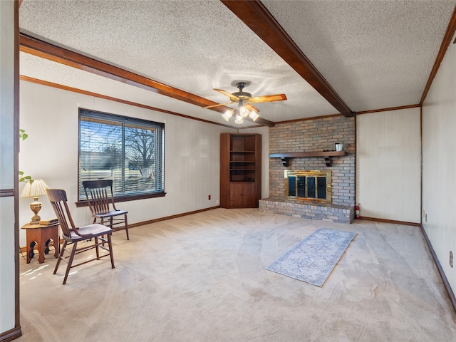 carpeted living room featuring beam ceiling, ceiling fan, crown molding, a textured ceiling, and a fireplace