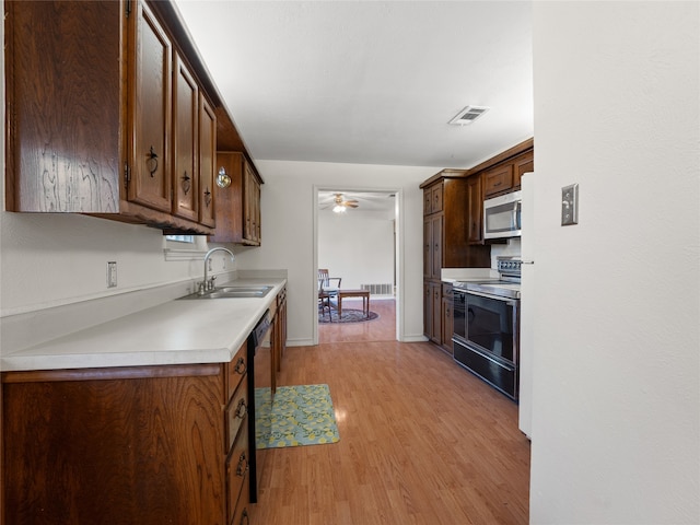 kitchen with ceiling fan, black electric range oven, sink, and light hardwood / wood-style flooring