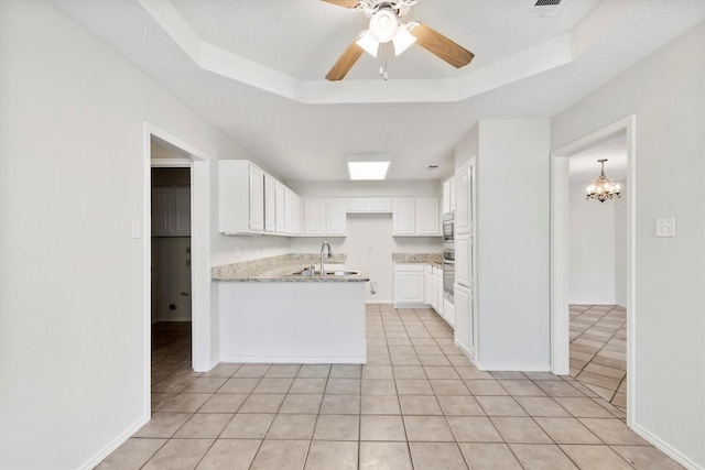 kitchen with white cabinets, light tile patterned floors, and a tray ceiling