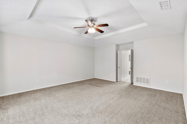 empty room with ceiling fan, a tray ceiling, and carpet floors