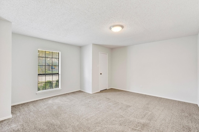 empty room with a textured ceiling and light colored carpet