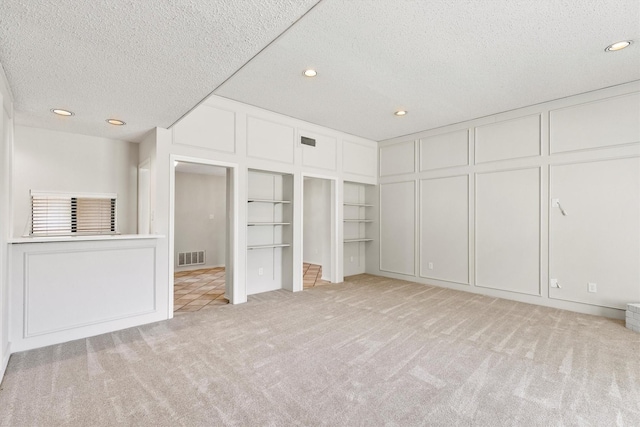 unfurnished bedroom featuring light colored carpet and a textured ceiling