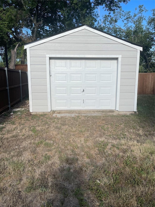 detached garage featuring driveway and fence