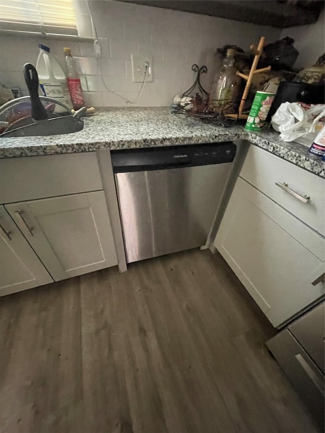 kitchen with sink, stainless steel dishwasher, dark hardwood / wood-style floors, light stone counters, and white cabinetry