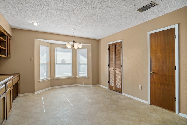 unfurnished dining area with a textured ceiling and an inviting chandelier