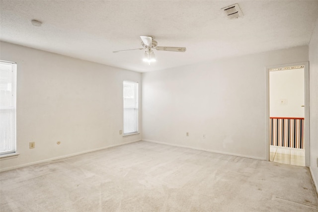 carpeted spare room featuring plenty of natural light and ceiling fan