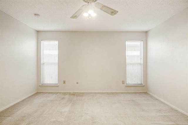 carpeted empty room with plenty of natural light, ceiling fan, and a textured ceiling