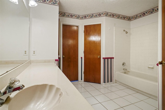 bathroom featuring tile patterned flooring, vanity, a textured ceiling, and tiled shower / bath combo