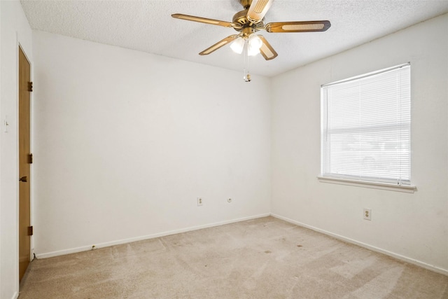 spare room featuring ceiling fan, light colored carpet, and a textured ceiling