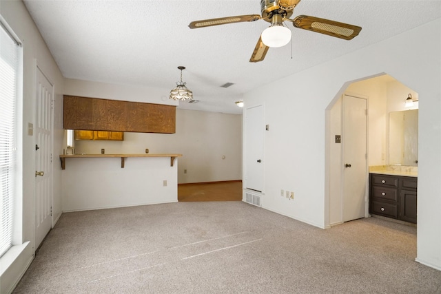 unfurnished living room with a textured ceiling, light colored carpet, and ceiling fan