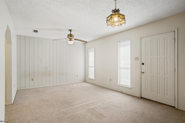 carpeted foyer entrance with ceiling fan, a healthy amount of sunlight, and a textured ceiling