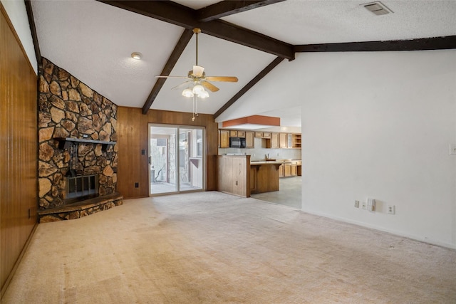 unfurnished living room featuring wood walls, a fireplace, light colored carpet, and a textured ceiling