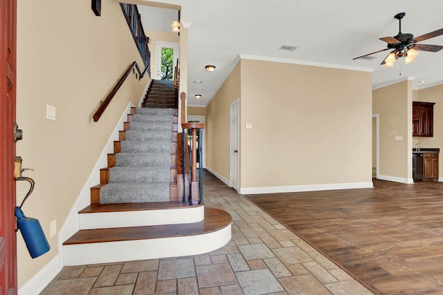 staircase featuring wood-type flooring, ceiling fan, and ornamental molding