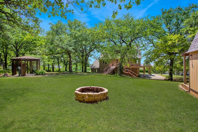 view of yard with a gazebo, a wooden deck, and a fire pit