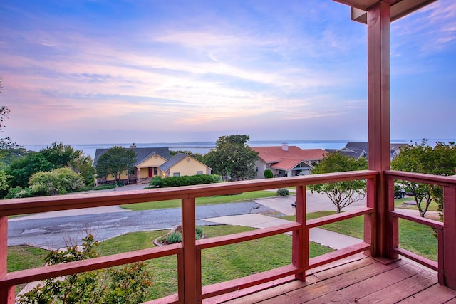 deck at dusk featuring a water view