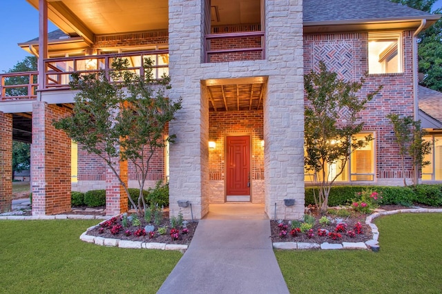 property entrance with a lawn and a balcony