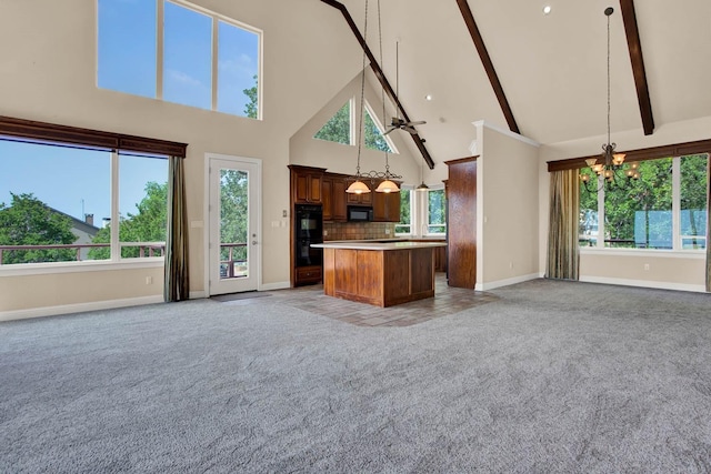 kitchen featuring tasteful backsplash, high vaulted ceiling, pendant lighting, a kitchen island, and black appliances