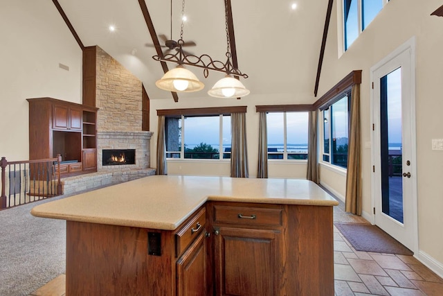 kitchen with a kitchen island, a stone fireplace, hanging light fixtures, and high vaulted ceiling