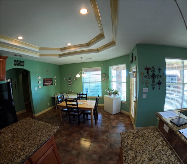 dining room featuring a tray ceiling, dark tile patterned floors, and ornamental molding