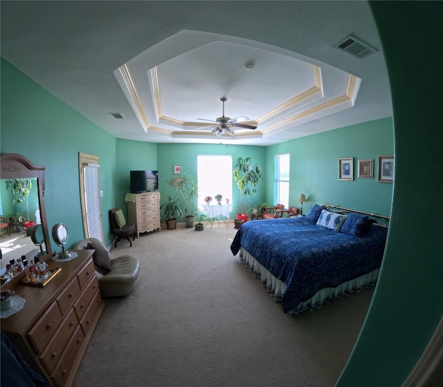 bedroom with carpet flooring, ceiling fan, ornamental molding, and a tray ceiling