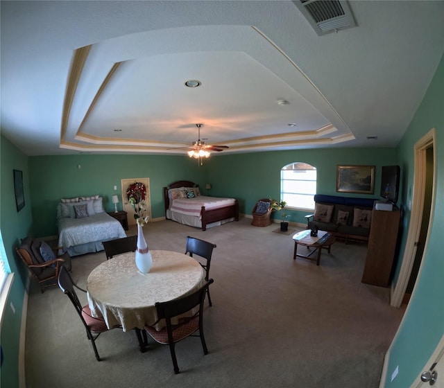 carpeted bedroom with a tray ceiling and ceiling fan