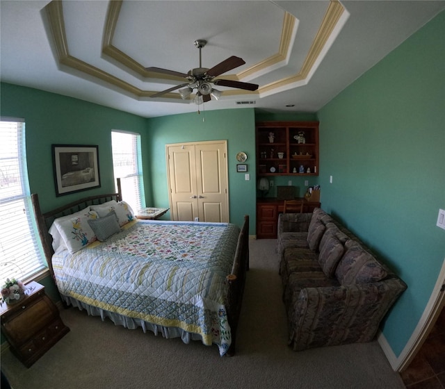 bedroom with multiple windows, a raised ceiling, and ceiling fan