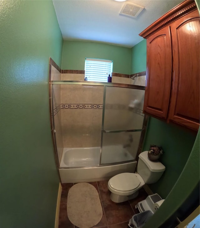 bathroom featuring tile patterned floors, toilet, and enclosed tub / shower combo