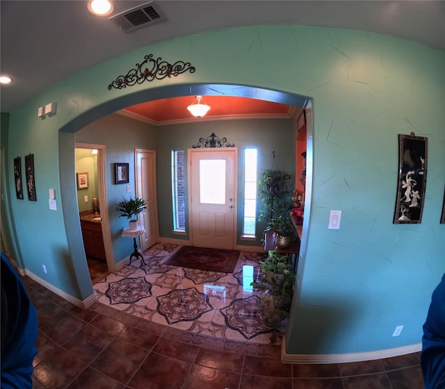 entrance foyer with dark tile patterned flooring and ornamental molding