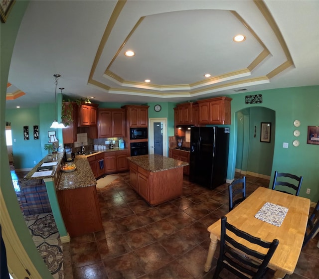 kitchen with a raised ceiling, kitchen peninsula, decorative light fixtures, a kitchen island, and black appliances