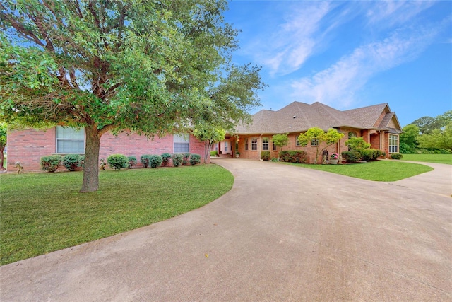 view of front of home with driveway, brick siding, and a front yard