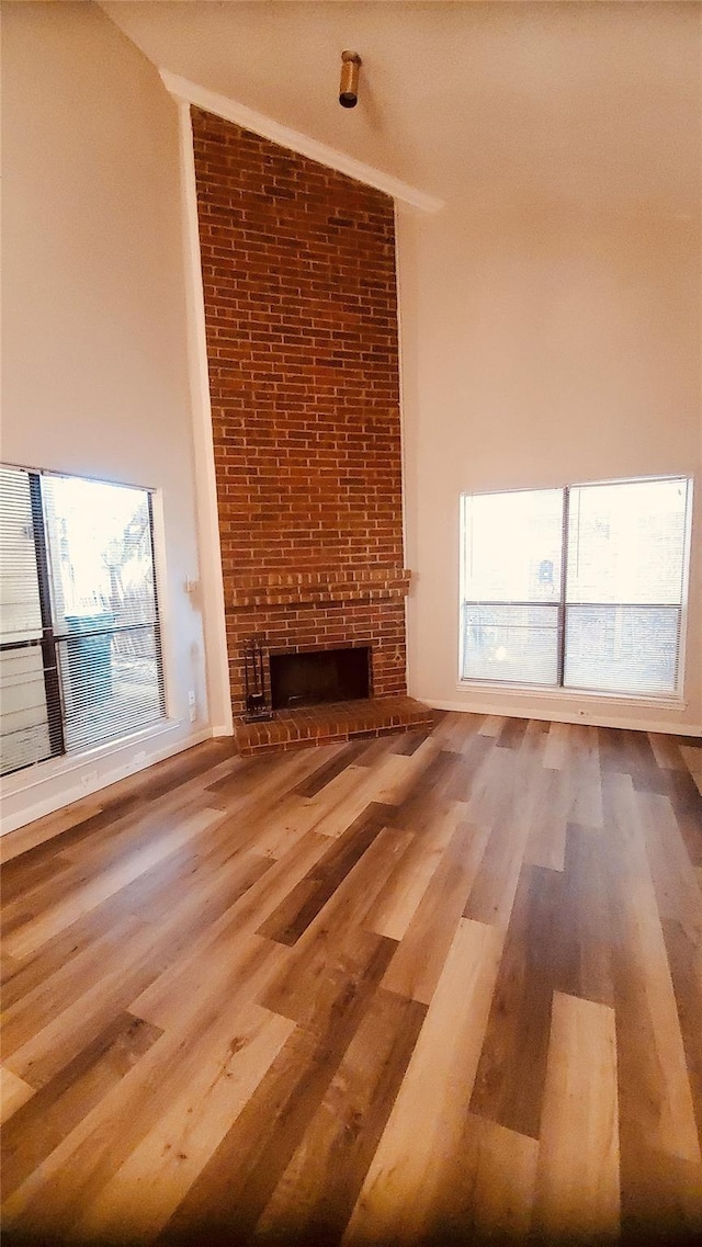 unfurnished living room featuring a fireplace, wood-type flooring, vaulted ceiling, and a wealth of natural light