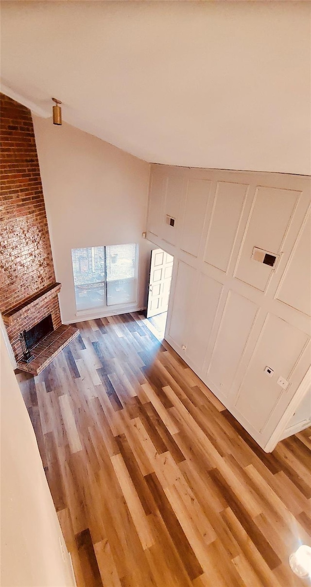 unfurnished living room featuring hardwood / wood-style floors and a brick fireplace