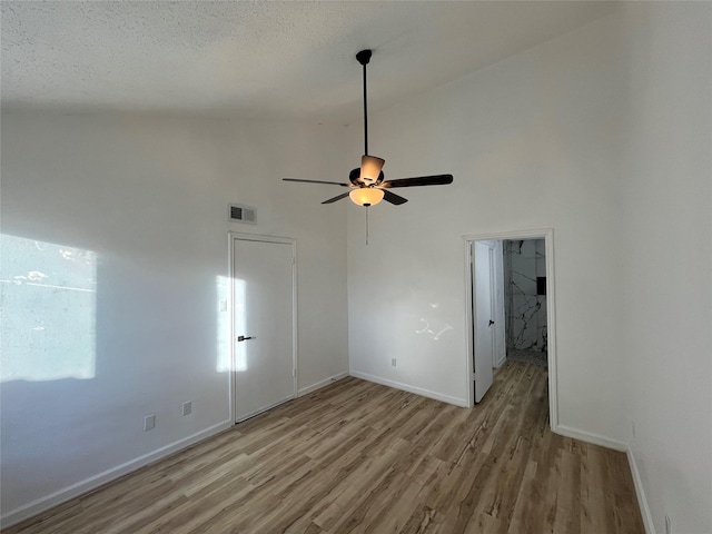 spare room with high vaulted ceiling, a textured ceiling, light hardwood / wood-style floors, and ceiling fan