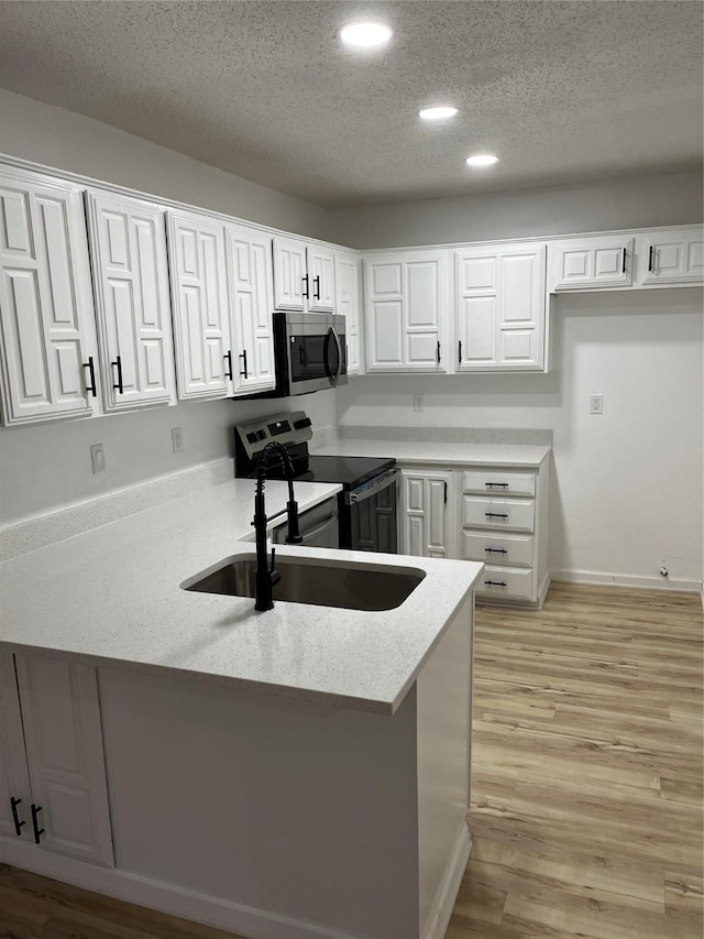 kitchen featuring stainless steel appliances, kitchen peninsula, a textured ceiling, and white cabinets